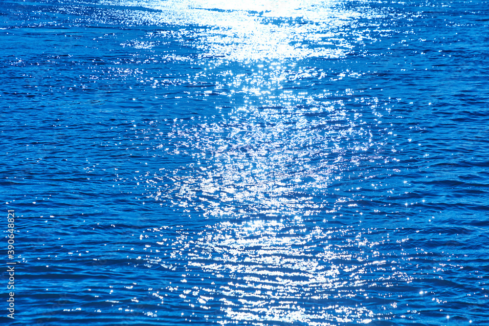 Sonnenstrahlen spiegeln sich auf einer bewegten Wasseroberfläche.