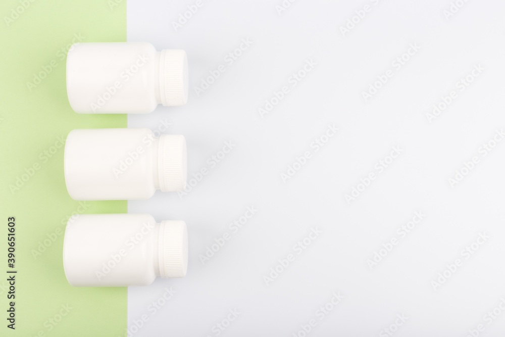 Obraz premium Flat lay with three unbranded jars with medication on light green and white background