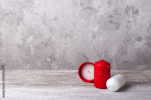 two red and white candles on a wooden table, one candle in a clay pot on the side, with a text area, copy space.