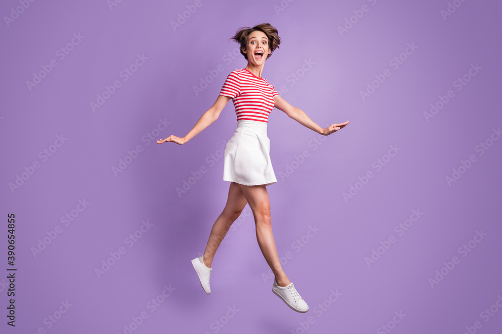 Full length profile photo of girl jump open mouth wear striped t-shirt mini skirt footwear isolated violet color background Full length profile photo of girl jump open mouth wear striped t-shirt mini skirt footwear isolated violet color background