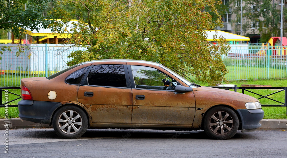 Old rusty car in the courtyard of a residential building