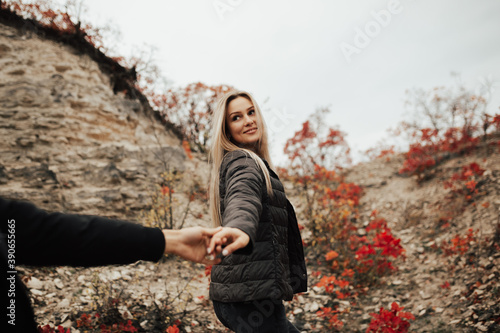 Obraz na płótnie Smiling girl pulling man's hand on the rocky mountain. Follow me. w salonie