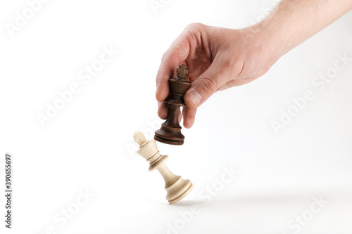 hand holds a chess king piece and defeats another king