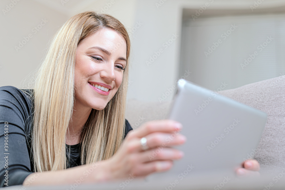 Beautiful girl uses a tablet pc while lying on the couch. Beautiful girl uses a tablet pc while lying on the couch.