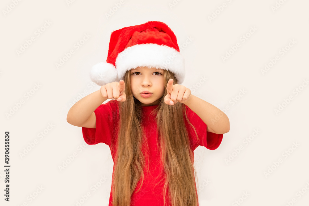 A little happy girl in a new year's hat points her fingers forward.