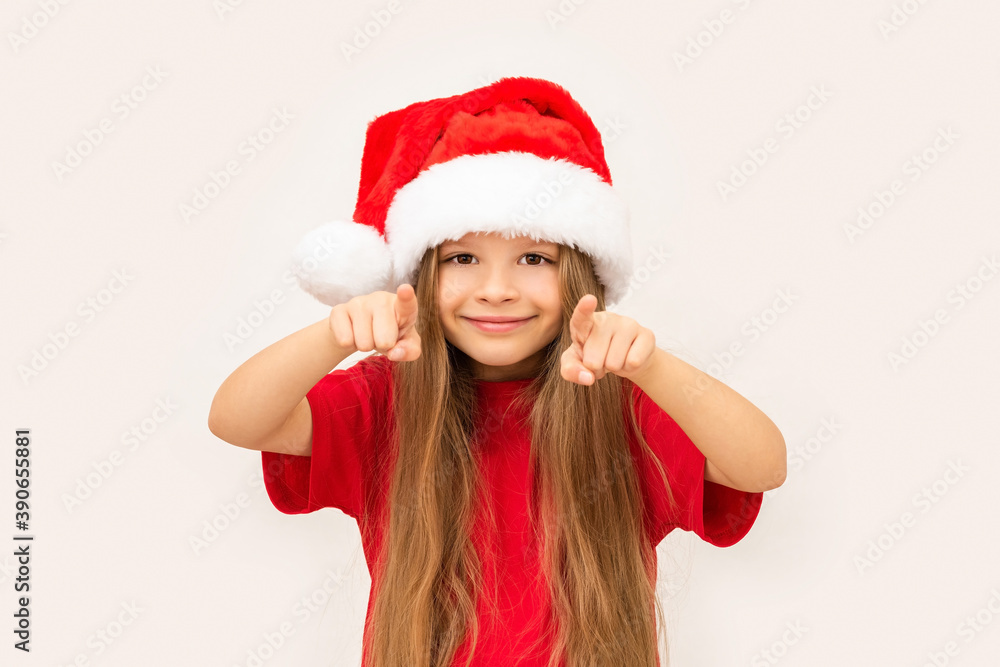 A little happy girl in a new year's hat points her fingers forward. A little happy girl in a new year's hat points her fingers forward.