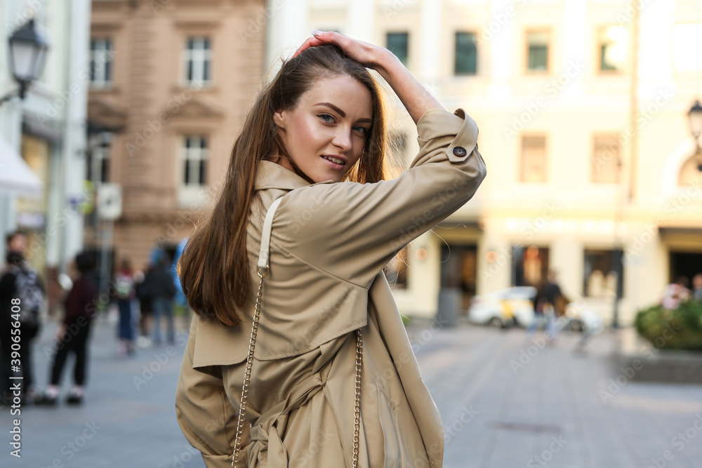 Fototapeta premium young beautiful woman walks in the city and straightens her hair