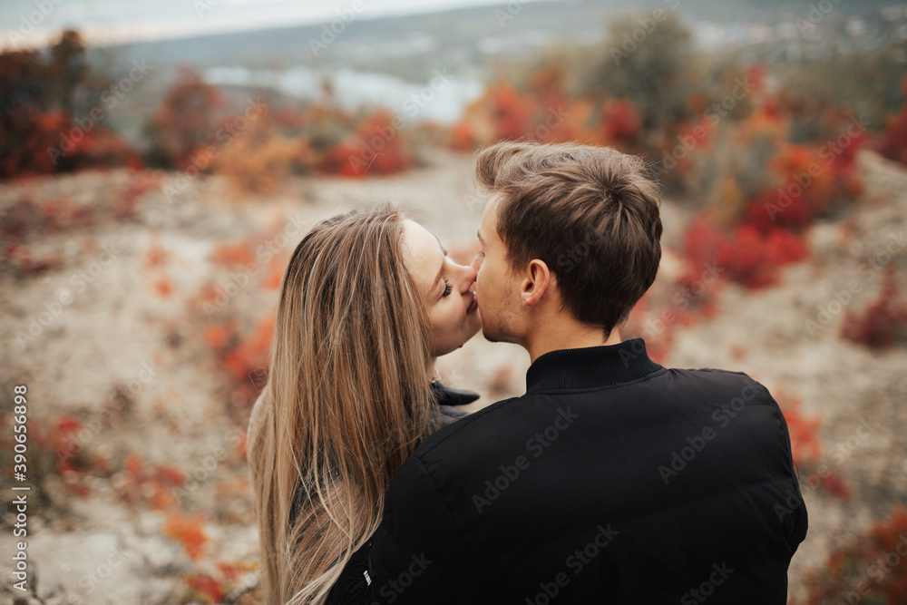 Fototapeta premium Romantic couple hugging at each other and want to kiss while sitting on the rocks in the mountain in fall season.