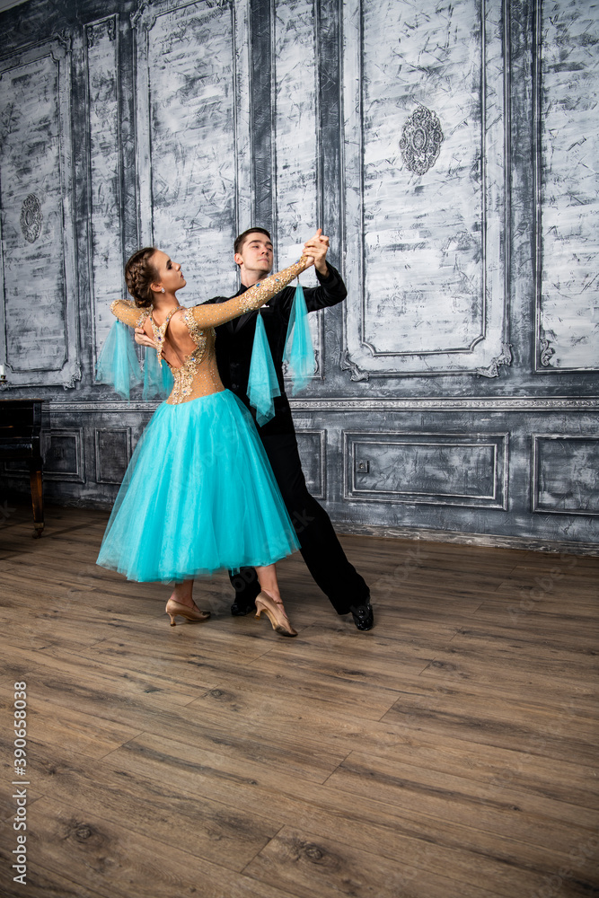 a young man in a black suit is dancing with a girl in a turquoise dress in the dance hall