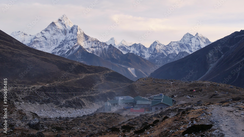 Panoramic view of majestic snow-capped Himalayan mountain range with mighty Ama Dablam (peak: 6,812 m) and Sherpa lodges at Dughla (Thukla) with smoking chimneys in Sagarmatha National Park, Nepal.