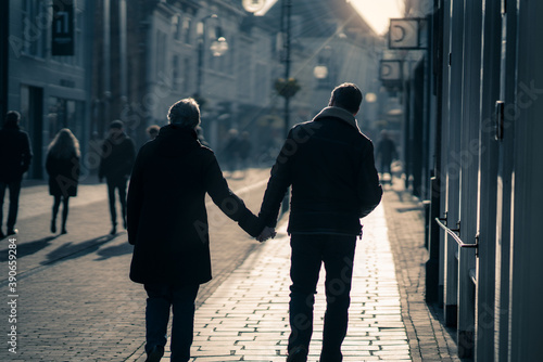 two people walking, holding hands in an old dutch city