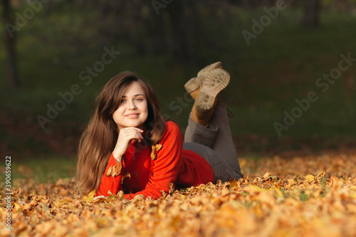 happy woman lying on fallen autumn leaves in forest  outdoor portrait