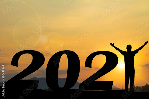 Happy new year Silhouette sunset background. He is wearing graduate's dress and standing instead number 1 word. A man standing next to 2.new year,success,2021,Photo Silhouette and new year.