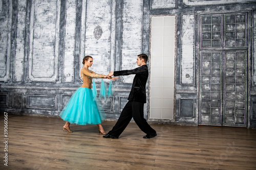 a young man in a black suit is dancing with a girl in a turquoise dress in the dance hall