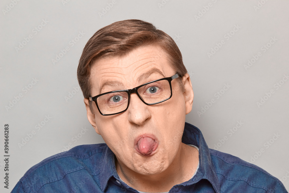 Portrait of disgruntled mature man showing tongue and teasing