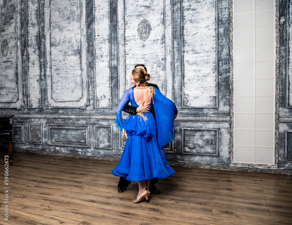 young man dancing with a girl in a blue ballroom dress in a gray dance hall young man dancing with a girl in a blue ballroom dress in a gray dance hall