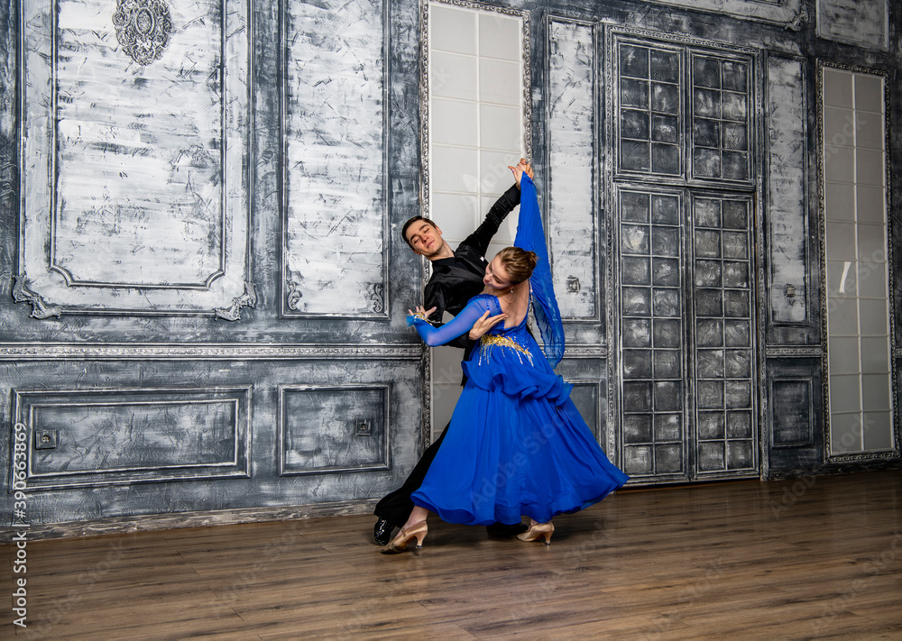 young man dancing with a girl in a blue ballroom dress in a gray dance hall young man dancing with a girl in a blue ballroom dress in a gray dance hall