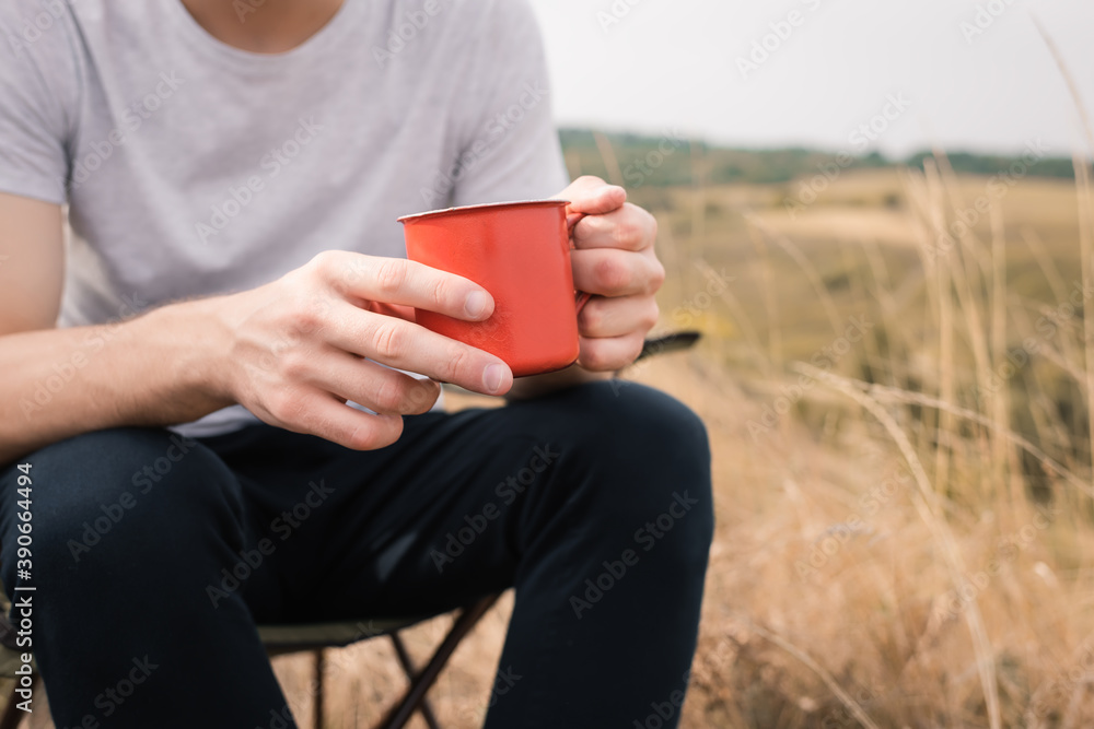 Cropped view of man holding cup while sitting on chair on lawn Cropped view of man holding cup while sitting on chair on lawn