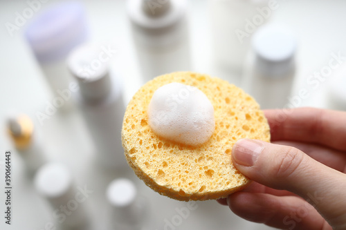 Yellow sponge with foam for the face in a woman's hand