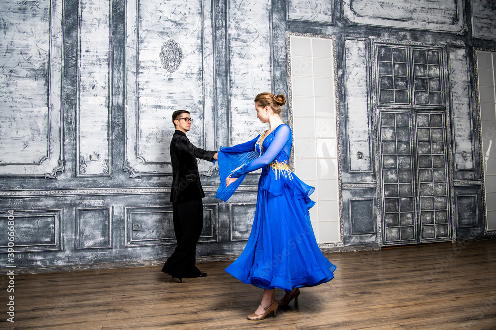 young man dancing with a girl in a blue ballroom dress in a gray dance hall young man dancing with a girl in a blue ballroom dress in a gray dance hall