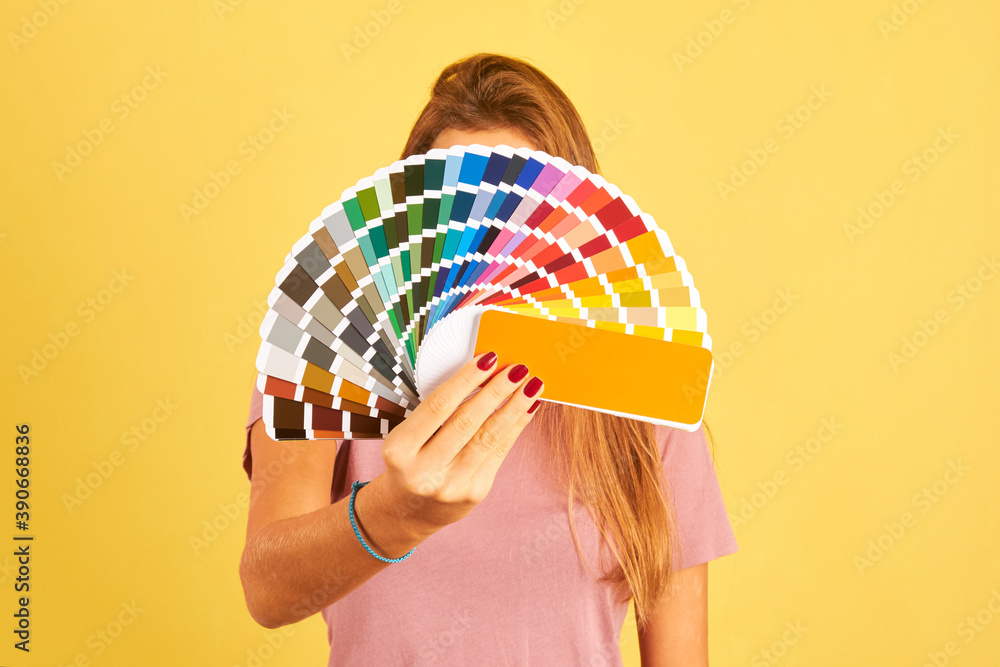 Fototapeta premium interior designer woman holding a color guide palette isolated on yellow background
