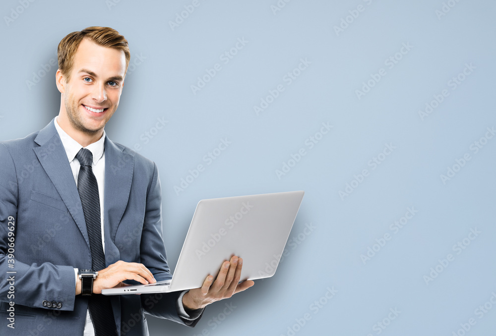 Portrait image of happy smiling confident businessman working with laptop, against grey color background. Success in business concept studio picture. IT professional specialist man. Portrait image of happy smiling confident businessman working with laptop, against grey color background. Success in business concept studio picture. IT professional specialist man.
