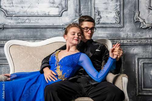 young couple in evening dresses sitting on a white couch in the dance hall © константин константи