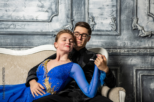 young couple in evening dresses sitting on a white couch in the dance hall