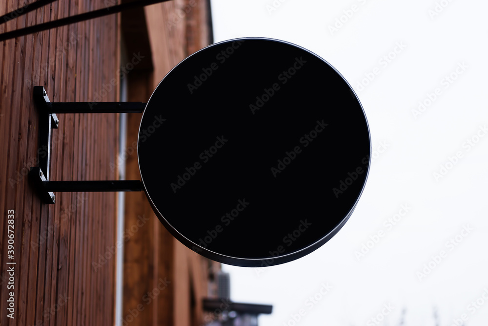 black round empty signboard on the wall outside the building for cafe, shop, salon black round empty signboard on the wall outside the building for cafe, shop, salon