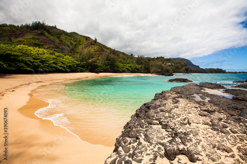 Laval rocks and headland on a Hawaiian coastline and a sweeping sandy beach. photo