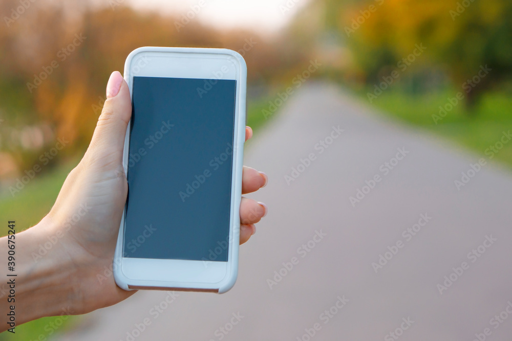 Smartphone in female hand  on autumn  background,with copy space.