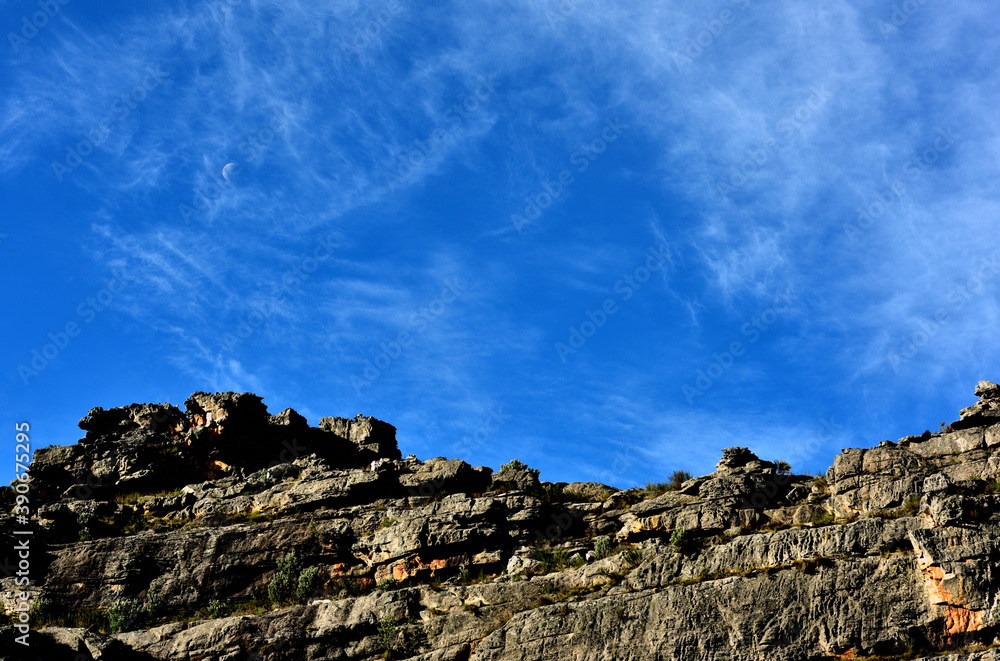 Rock cliff against blue sky with clouds and a day moon in the Cederberg South Africa Rock cliff against blue sky with clouds and a day moon in the Cederberg South Africa