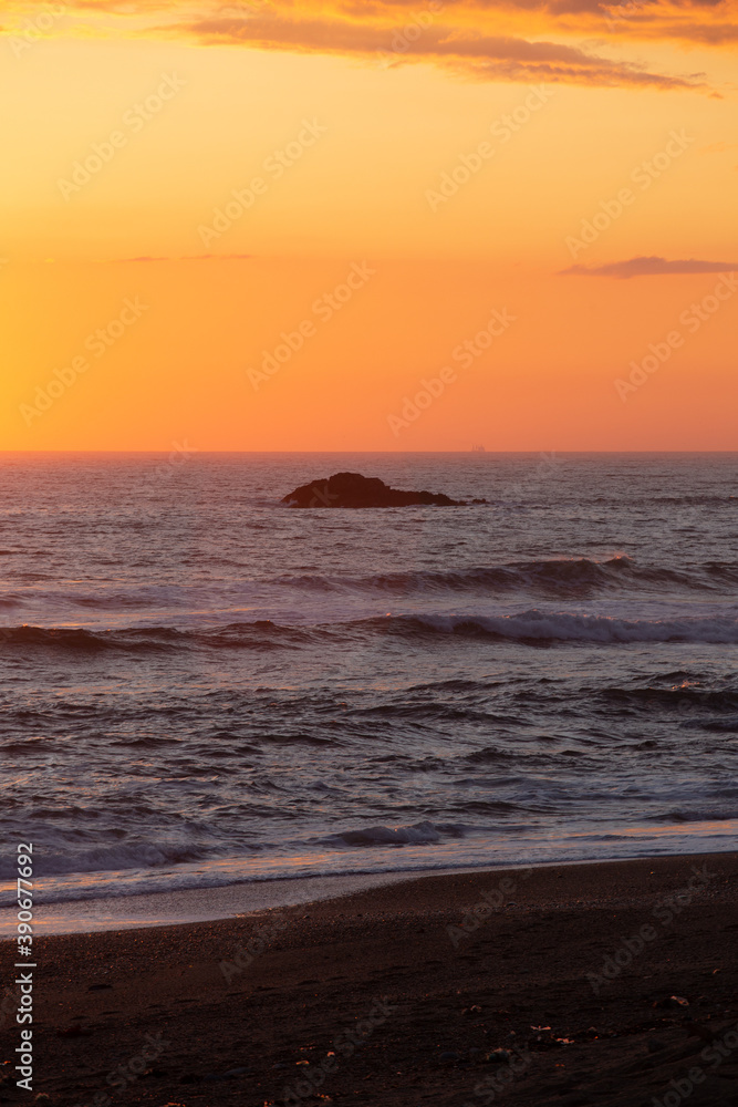 Sunset over the ocean with a rock