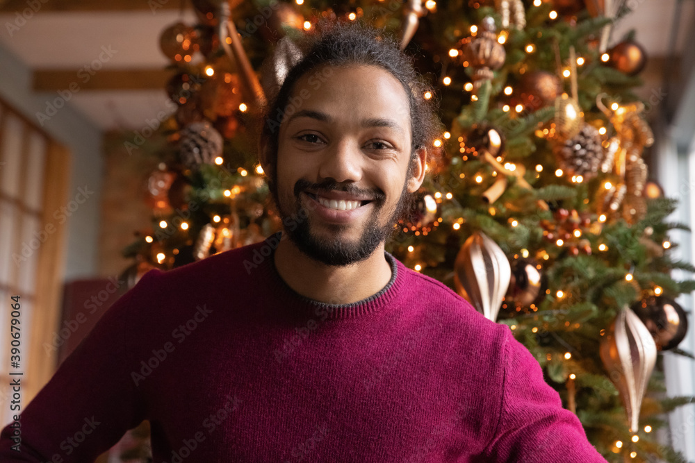 Head shot portrait smiling African American man chatting online with Christmas tree on background, making video call to relatives or friends, using webcam, blogger recording vlog for social network Head shot portrait smiling African American man chatting online with Christmas tree on background, making video call to relatives or friends, using webcam, blogger recording vlog for social network