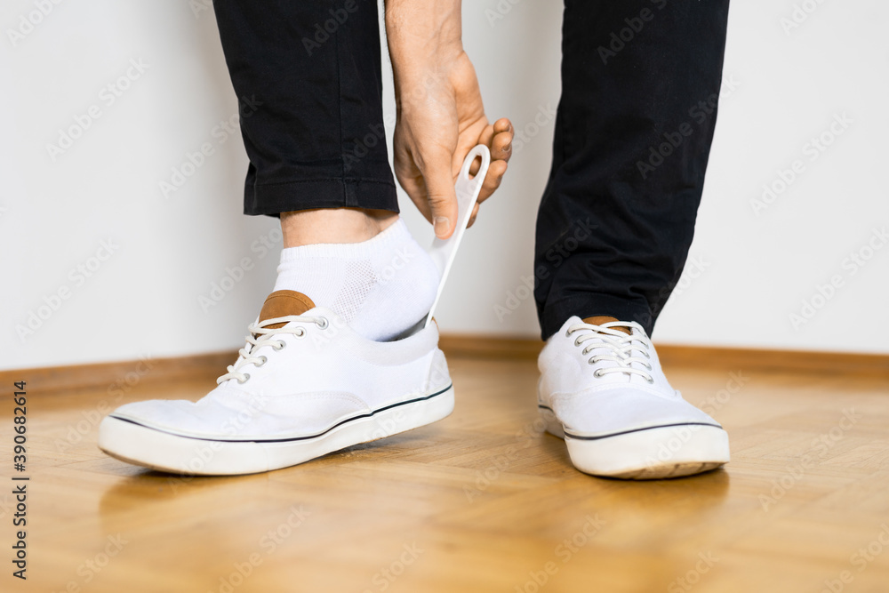 put on shoes with shoespooner on wooden floor by a man with black pants legs put on shoes with shoespooner on wooden floor by a man with black pants legs