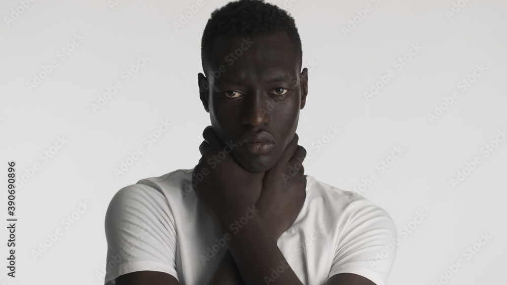 Obraz premium Young African American man holding hands on neck aggressively looking in camera over white background. Choke expression. Black lives matter