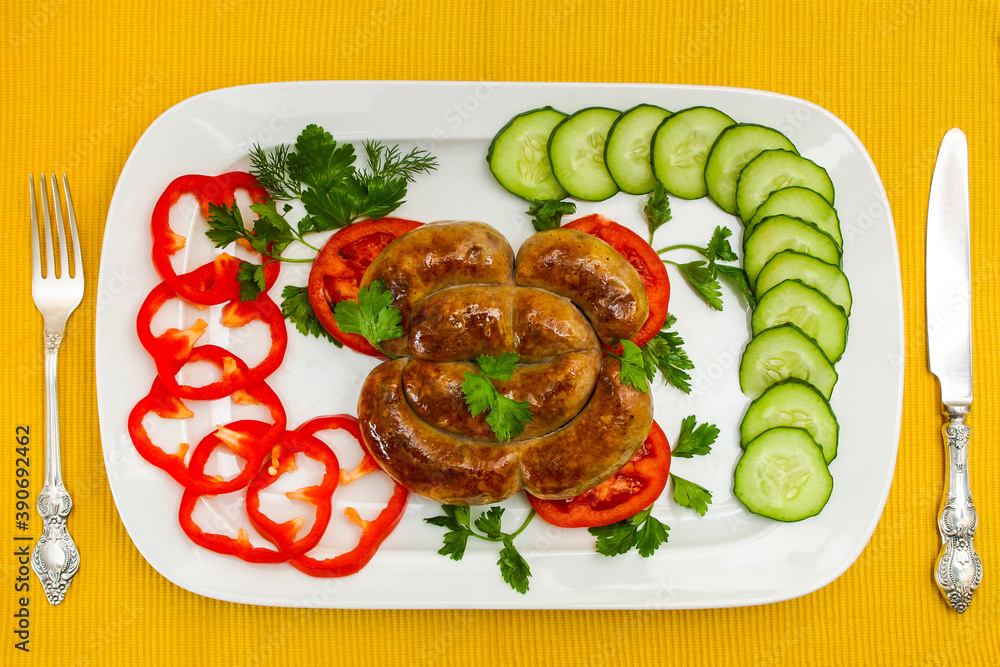 Fried pork sausage on a white plate. Composition with fresh cutted vegetables on a yellow tablecloth