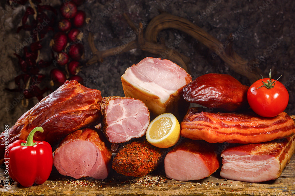 A variety of meat products including pork, beef and fresh vegetables on a old wooden table and dark painted background