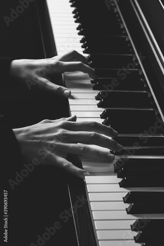 Two hand on a piano keyboard, vertical black and white photo