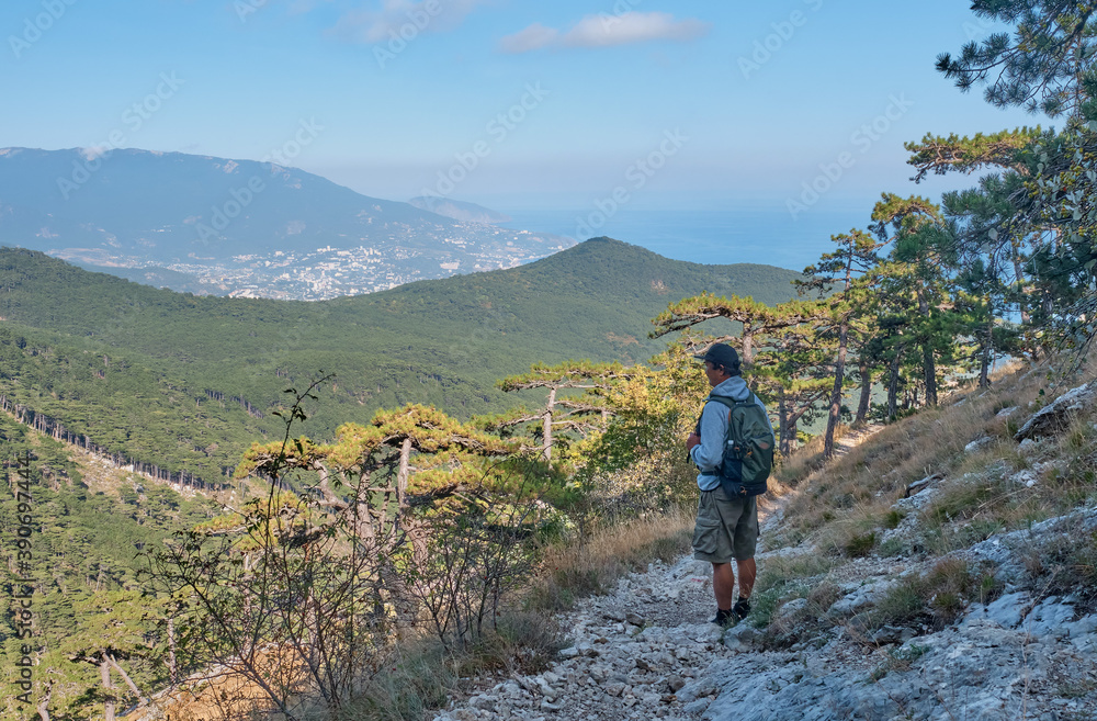 the southern Crimea. Scenic slope of Ai Petri mountain. A man with a backpack is walking along the rocky mountain trail.