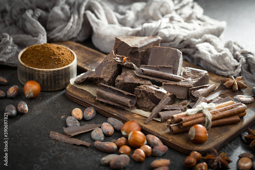 Pieces of dark chocolate and cocoa beans in composition on old background