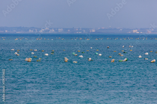 Sea in Taiwan with floating plastic. Fishermen set up nets. Garbage in the sea. © frolova_elena