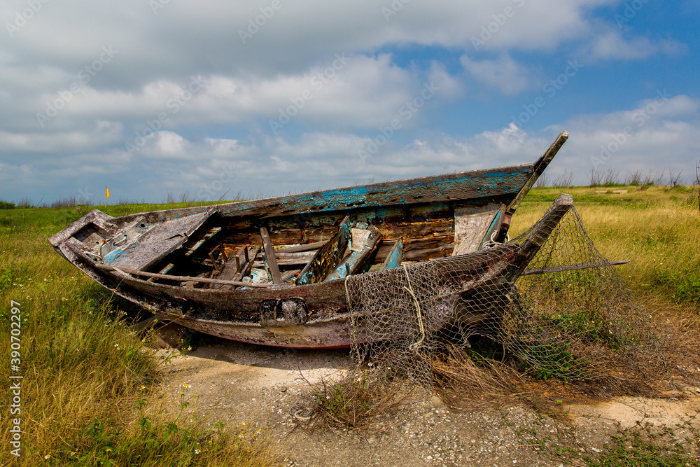 Abandoned fishing wooden boat with a net on the field Abandoned fishing wooden boat with a net on the field