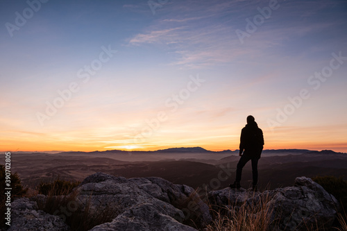 Silhouette of a person at the top of the mountains looking at sunrise © Juan Baena