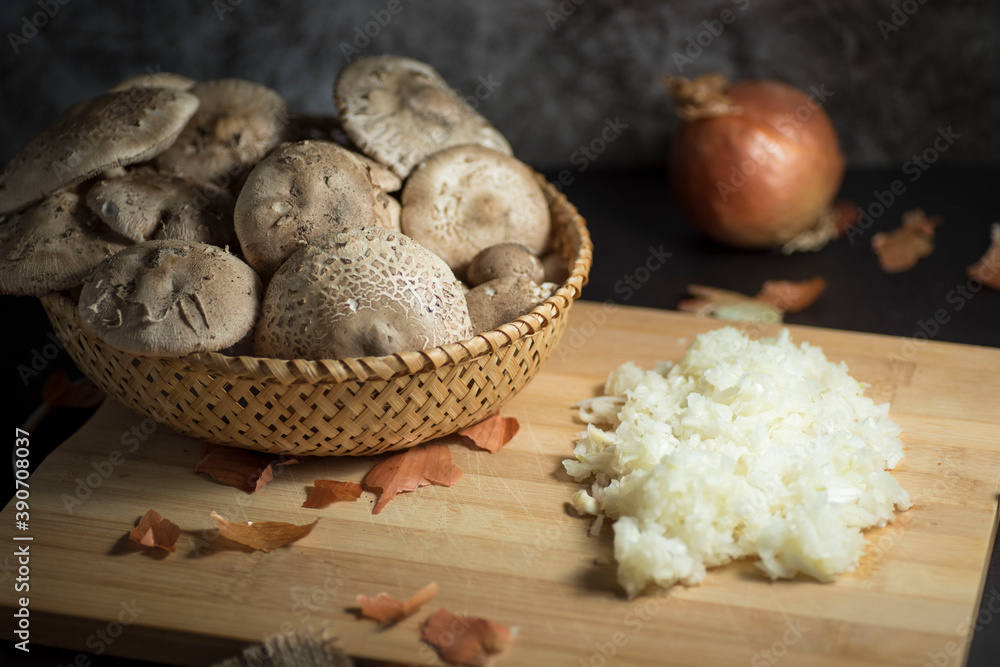 Closeup of fresh white mushrooms in a basket with chopped onions on a cutting board Closeup of fresh white mushrooms in a basket with chopped onions on a cutting board