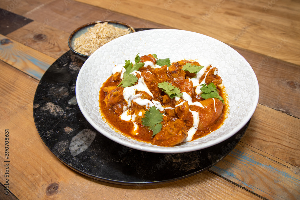 A plate delicious Butter Chilli chicken with rice on a wooden kitchen work top. A plate delicious Butter Chilli chicken with rice on a wooden kitchen work top.