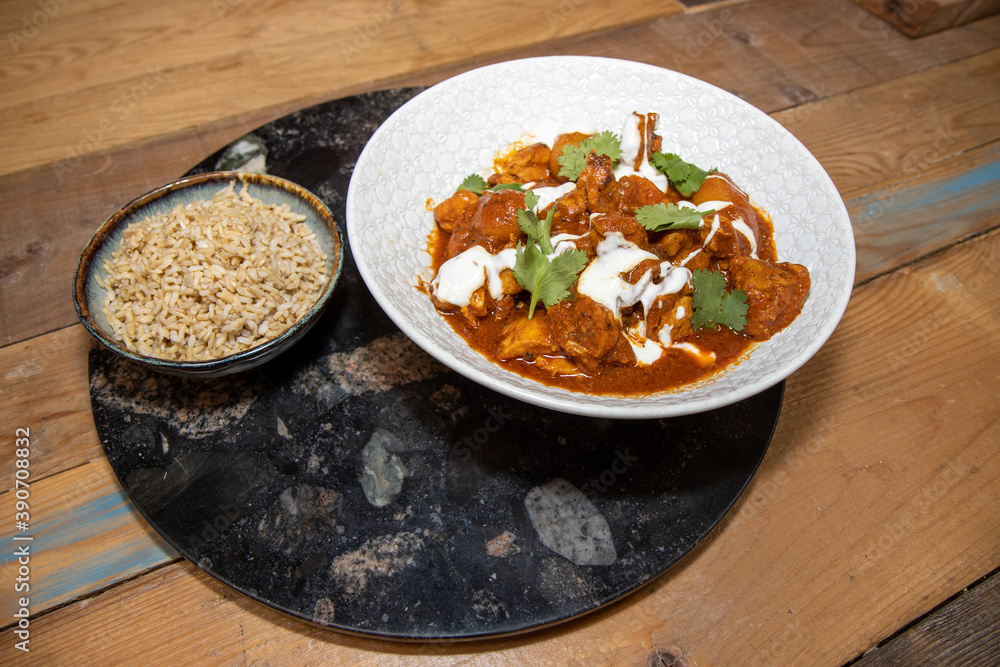 A plate delicious Butter Chilli chicken with rice on a wooden kitchen work top. A plate delicious Butter Chilli chicken with rice on a wooden kitchen work top.