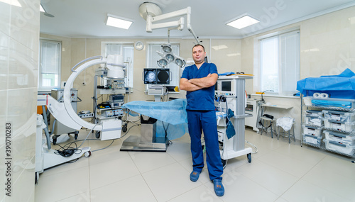 Portrait of a male surgeon at work. Modern surgery room at clinic. Professional doctor in up to date medic equipment background.