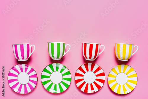Set of color plates and mugs with  a stripes pattern  on pink background.  