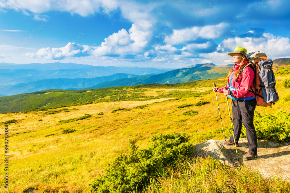 Happy traveling woman with backpack looking at mountain landscape